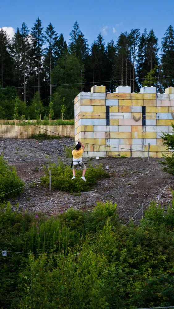 Personne sur une tyrolienne en face de la forteresse au parc acrobatique des Vieilles Forges